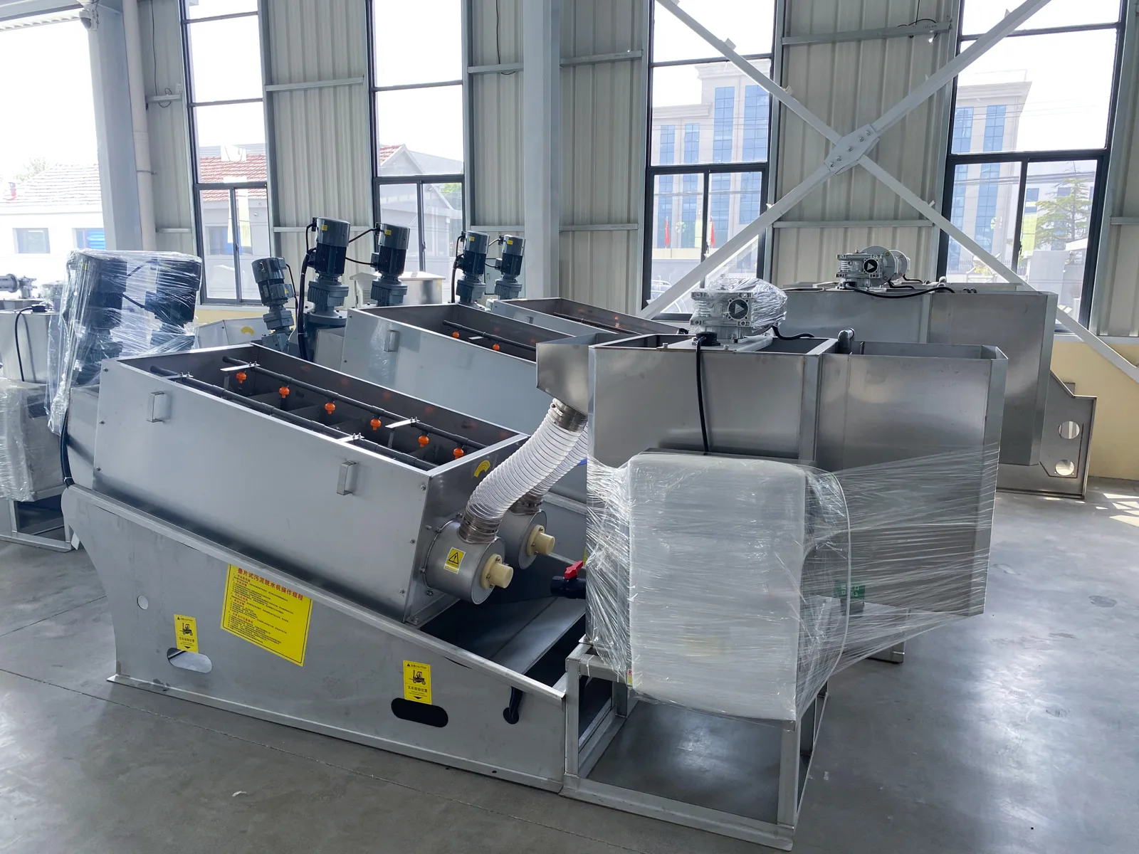 CXDL screw presses on the workshop floor in our factory, each with its tank and inclined pressing cylinder on a stainless steel frame